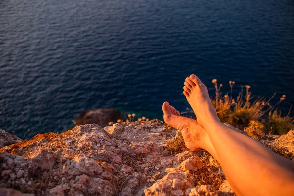Kadın bacakları gün batımında uçurumda deniz tatili
