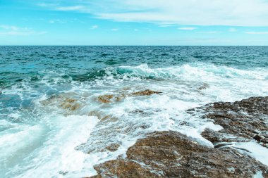 Beyaz köpüklü kayalık deniz dalgalarının manzarası. Boşluğu kopyala
