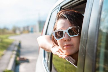 Kadın arabanın camından dışarı bakıyor. Yolculuk konsepti. Yaz güneşli bir gün