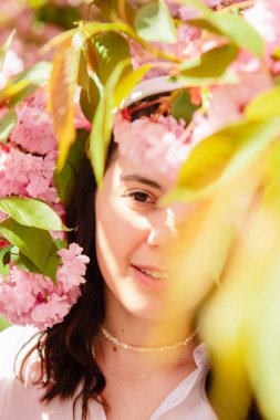 Muhteşem beyaz kadın, çiçek açan pembe sakura ağacının altında fotokopi alanı.