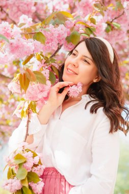 Muhteşem beyaz kadın, çiçek açan pembe sakura ağacının altında fotokopi alanı.