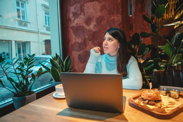 喫茶店でノートパソコンで働くフリーランサー女性お茶を飲むバーガーコピースペース — ストック写真