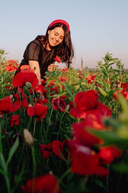 Haşhaş tarlasında gün batımında siyah elbiseli güzel bir kadın.