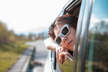 Kadın arabanın camından dışarı bakıyor. Yolculuk konsepti. Yaz güneşli bir gün