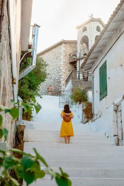 Seyahat ve aktif yaşam tarzı konsepti. Sarı elbiseli genç bir kadın. Eski Yunan kasabasında yürüyor..