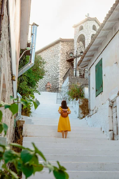 旅行やアクティブなライフスタイルの概念 若いです旅行者女性で黄色のドレスバックビューで歩くと古いギリシャの町 — ストック写真