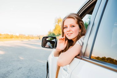 Gün batımında araba süren genç ve güzel bir kadın. Sıcak güneşli bir gün
