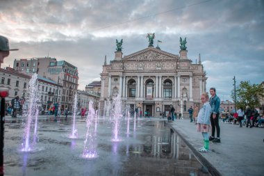 Lviv, Ukrayna - 14 Mayıs 2021: İnsanlar opera binası çeşmesinin önünde şehir meydanından yürüyorlar