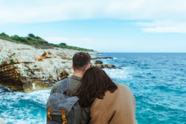 Uçurumda oturup denize bakan çift. büyük dalgalar.