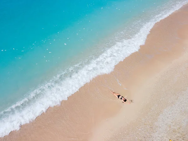 身穿黑色泳衣的女子在海滨沙滩晒日光浴的俯瞰图 — 图库照片