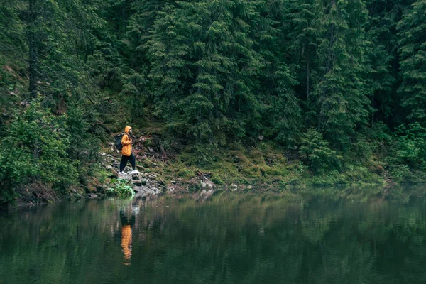 湖滨山林黄衣女徒步旅行者 — 图库照片