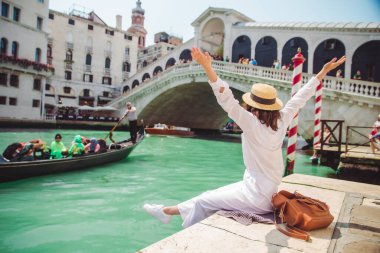 Venedik 'te rialto köprüsünün yanında oturan kadın gondollu Grand Canal' a bakıyor.