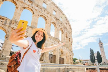 Hırvatistan 'ın Pula kentinde kolezyum önünde selfie çeken bir kadın. Yaz tatili. ünlü simge