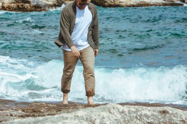 Rüzgarlı yaz tatilinde Rocky Beach 'te yürüyen bir adam. Deniz manzarasının tadını çıkar. yaz zamanı