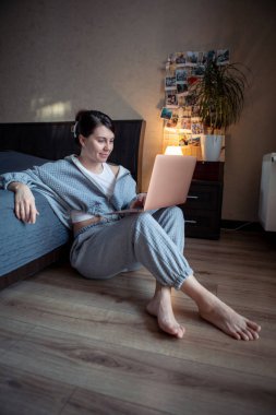Dizüstü bilgisayarda çalışan serbest çalışan bir kadın dizlerinin üzerinde oturuyor.