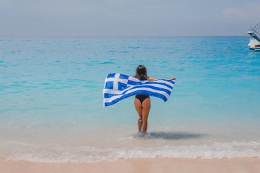 Deniz kıyısında koşan mutlu seksi kadın. Yunan bayrağıyla yaz tatili.
