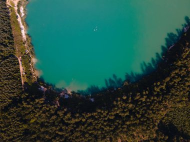 Ormanın yakınında mavi suyu olan göl manzarası.