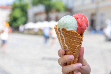 Sıcak yaz gününde elinde eriyen dondurmayı tutan kadın.