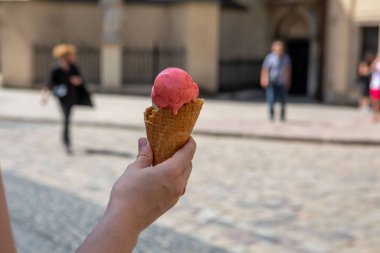 Sıcak yaz gününde elinde eriyen dondurmayı tutan kadın.