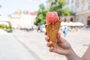 Sıcak yaz gününde elinde eriyen dondurmayı tutan kadın.