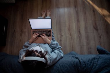 Evde çalışan serbest çalışan bir kadın. Beyaz perdenin üstünde oturuyor.