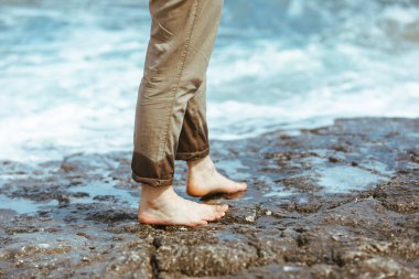 Deniz kıyısında yürürken pantolonlu ıslak adam bacakları suyun tadını çıkarıyor. yaz tatili