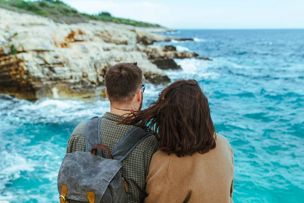 Uçurumda oturup denize bakan çift. büyük dalgalar.