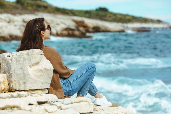 Uçurumun Kenarında Oturup Deniz Manzarasının Keyfini Çıkaran Kadın Rüzgarlı Hava — Stok fotoğraf