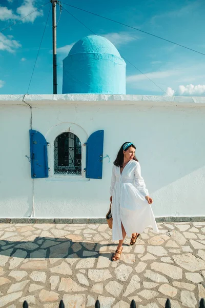 Eski Yunan kilisesinin yanında beyaz elbiseli güzel bir kadın. Mavi elbiseli.