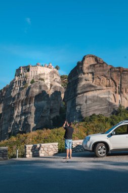 Yunanistan araba yolculuğu konsepti. Cipin yanında duran bir adam meteora manastırına bakıyor.