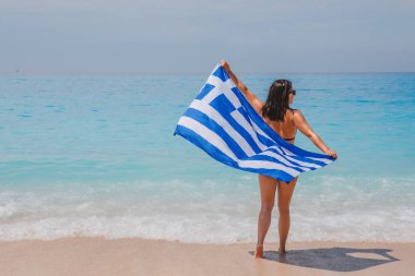 Deniz kıyısında koşan mutlu seksi kadın. Yunan bayrağıyla yaz tatili.