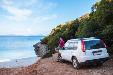 Deniz kıyısı gezisinde SUV arabalı bir adam.