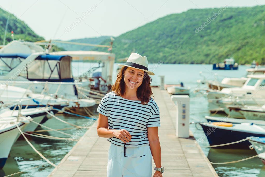 woman in white fashion luxury view walking by dock boats on background. summer time
