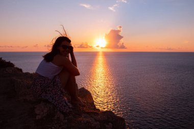 Kadınlar yaz tatilinde deniz üzerinde gün batımının keyfini çıkarırlar.