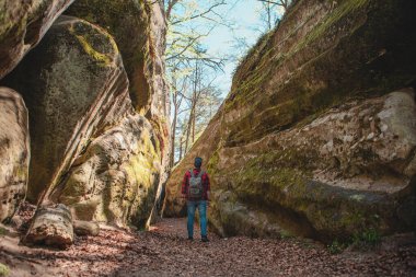Sırt çantalı bir adam Ukrayna 'daki kanyon güvercini kayalarında yürüyor.