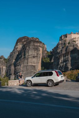 Yunanistan araba yolculuğu konsepti. Cipin yanında duran bir adam meteora manastırına bakıyor.