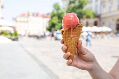 Sıcak yaz gününde elinde eriyen dondurmayı tutan kadın.