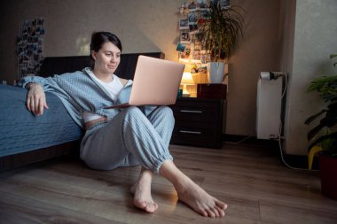 Dizüstü bilgisayarda çalışan serbest çalışan bir kadın dizlerinin üzerinde oturuyor.