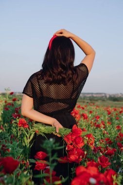 Haşhaş çiçeklerindeki kadın günbatımı tarlasında fotokopi uzayı
