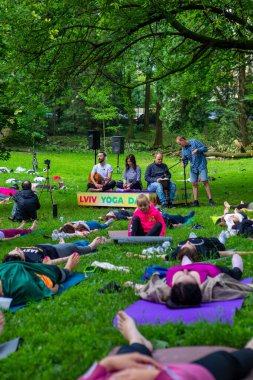 Lviv, Ukrayna - 2 Temmuz 2021: Şehir parkındaki birçok insan yoga yapıyor.