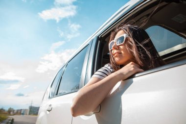 Kadın arabanın camından dışarı bakıyor. Yolculuk konsepti. Yaz güneşli bir gün