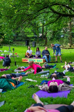 Lviv, Ukrayna - 2 Temmuz 2021: Şehir parkındaki birçok insan yoga yapıyor.