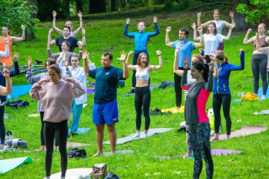 Lviv, Ukrayna - 2 Temmuz 2021: Şehir parkındaki birçok insan yoga yapıyor.