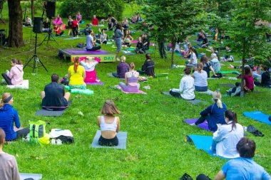 Lviv, Ukrayna - 2 Temmuz 2021: Şehir parkındaki birçok insan yoga yapıyor.