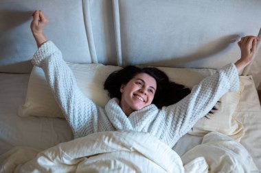morning in bed woman awaking laying down in bed with white sheets