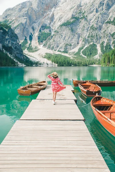 Joven mujer bonita vestido rojo caminando por muelle de madera con barcos. vacaciones de verano — Foto de Stock