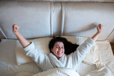 morning in bed woman awaking laying down in bed with white sheets bright room