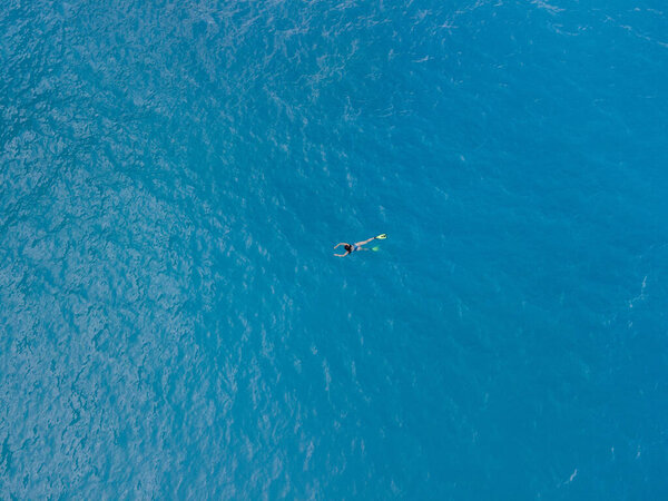 overhead view of woman swimming in flippers in blue sea water