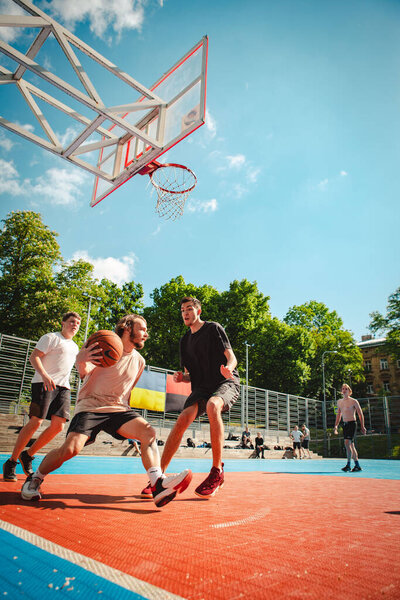 Lviv, Ukraine - May 28, 2022: men playing basketball outdoors sunny summer day