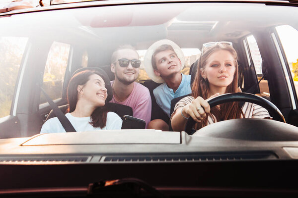 four friends in car navigation on phone. road trip